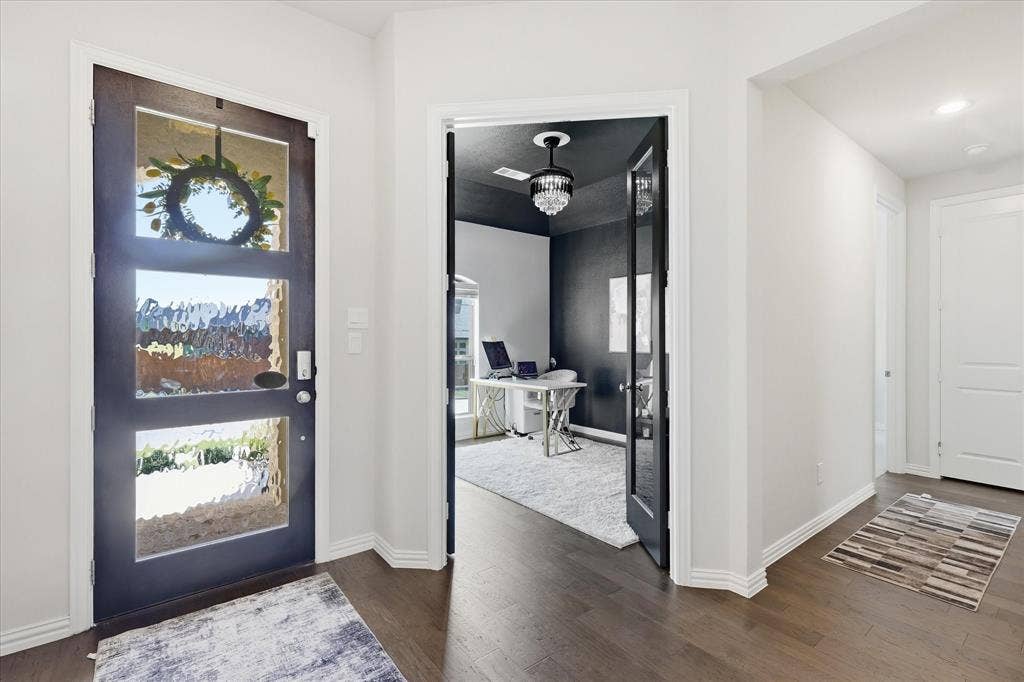 Wood-finish flooring, dark wood-finish entry door with textured glass panels, and an interior room with a chandelier
