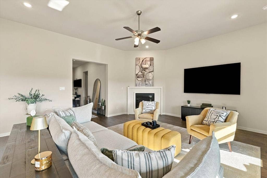Recessed lighting, ceiling fan, wood-finish flooring, white fireplace surround, and a wall-mounted entertainment console