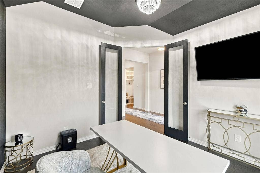 Dual opaque-paneled doors, dark wood-finish flooring, recessed lighting, and a crystal chandelier