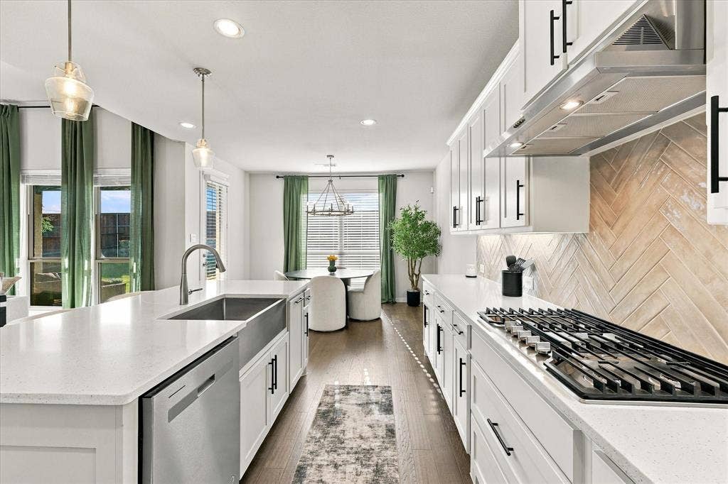 Kitchen featuring white shaker cabinetry, stainless steel appliances, wood-finish flooring, and a herringbone-patterned backsplash