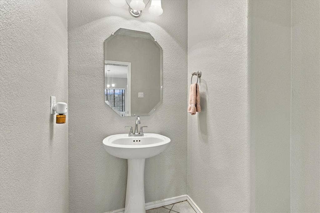 4716 Kendrick Peak Way, Fort Worth, TX 76244 Pedestal sink with chrome faucet, octagonal mirror, and overhead vanity lighting