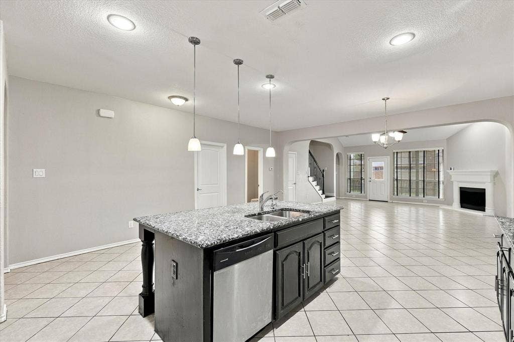 4716 Kendrick Peak Way, Fort Worth, TX 76244 Kitchen island featuring a double-basin sink, stainless steel dishwasher, and pendant lighting