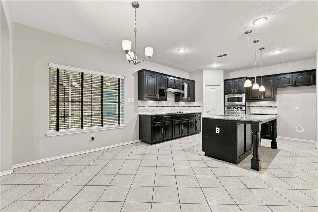 4716 Kendrick Peak Way, Fort Worth, TX 76244 Kitchen featuring black cabinetry, light-toned tile flooring, recessed lighting, a center island with pendant lighting, and stainless steel appliances