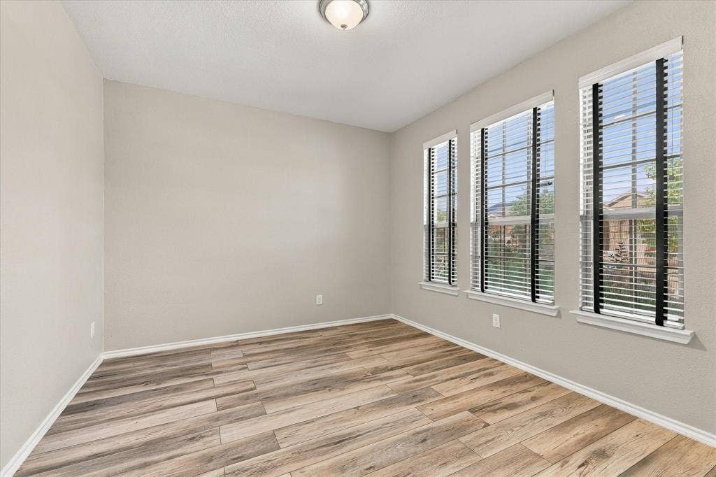 4716 Kendrick Peak Way, Fort Worth, TX 76244 Neutral wall paint, wood-finish flooring, and multiple windows with blinds