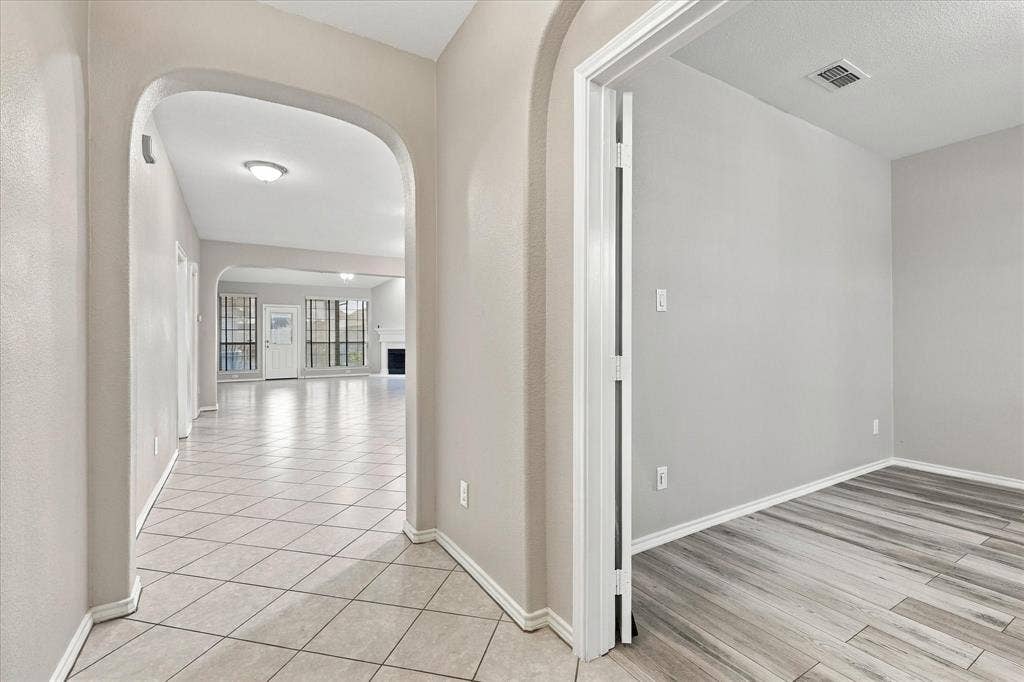 4716 Kendrick Peak Way, Fort Worth, TX 76244 Arched entryways delineate spaces, with tile flooring leading into a room featuring wood-finish flooring