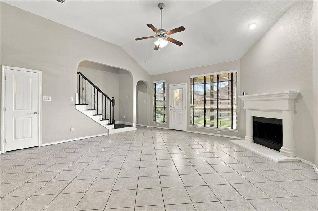 4716 Kendrick Peak Way, Fort Worth, TX 76244 Vaulted ceiling with a ceiling fan, tiled flooring, built-in fireplace, and a staircase with wrought iron balusters
