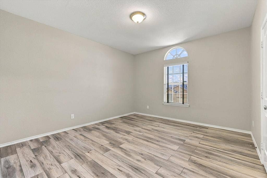 4716 Kendrick Peak Way, Fort Worth, TX 76244 Wood-finish flooring, neutral wall color, and arched window with blinds