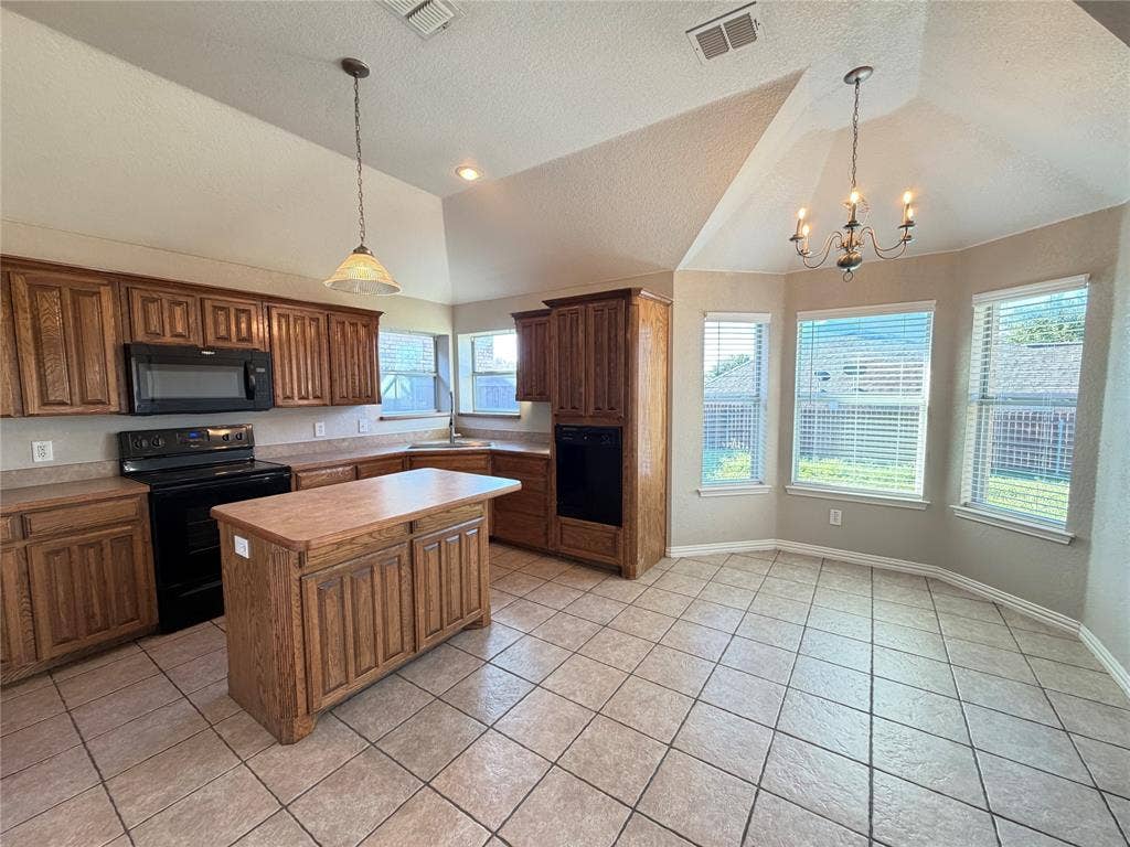 5932 Highcrest Drive, Watauga, TX 76148 Kitchen featuring wood cabinetry, a central island, black appliances, and neutral countertops