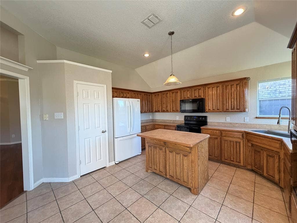 5932 Highcrest Drive, Watauga, TX 76148 Kitchen featuring a vaulted ceiling, recessed lighting, a central island, wood-finish cabinetry, and tiled flooring