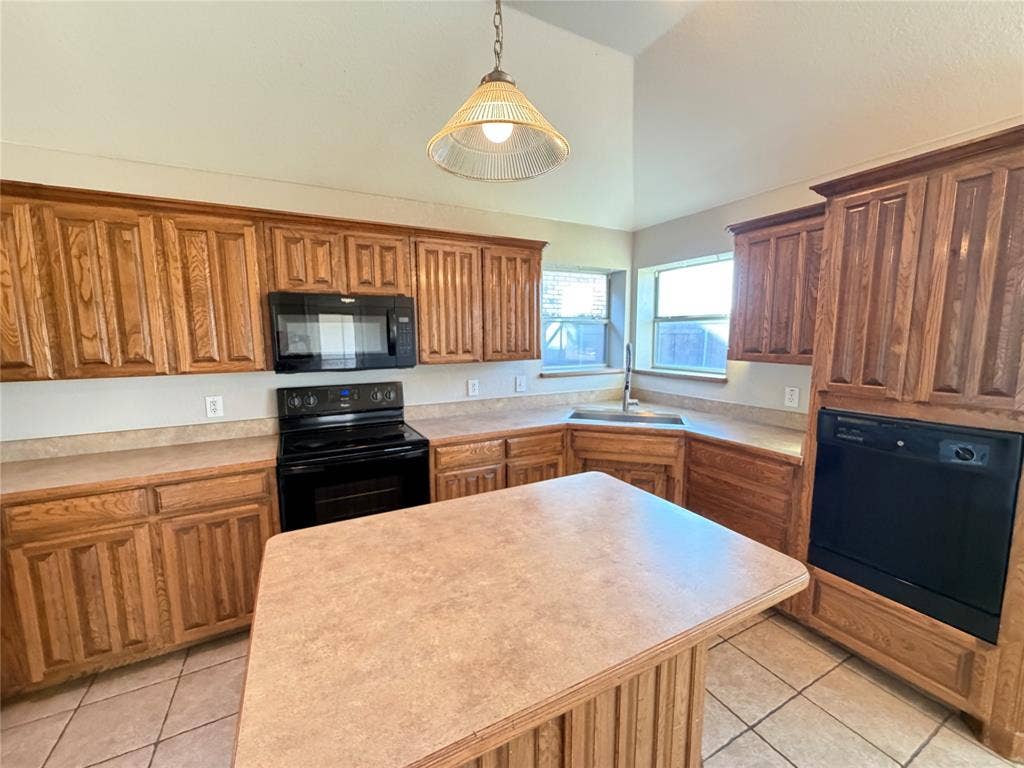5932 Highcrest Drive, Watauga, TX 76148 Kitchen featuring wood cabinetry, black appliances, a central island, and vaulted ceilings