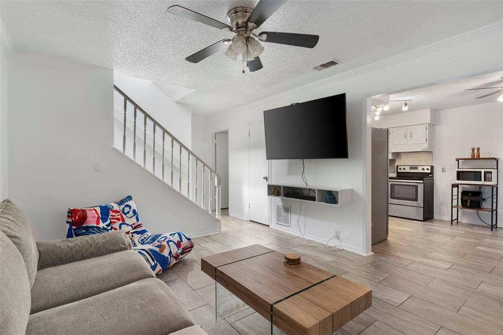 4414 Westminster Drive, Irving, TX 75038 Open-concept living area featuring wood-finish flooring, a contemporary ceiling fan, and a built-in wall shelf
