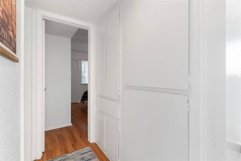 4414 Westminster Drive, Irving, TX 75038 Integrated white cabinetry with paneled doors, hardwood flooring, and white painted walls