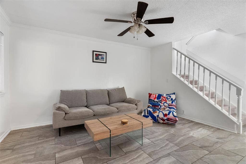 4414 Westminster Drive, Irving, TX 75038 Bright loft-style space featuring exposed ceiling with ceiling fan, wood-finish flooring with geometric tile pattern, and a gray upholstered sofa