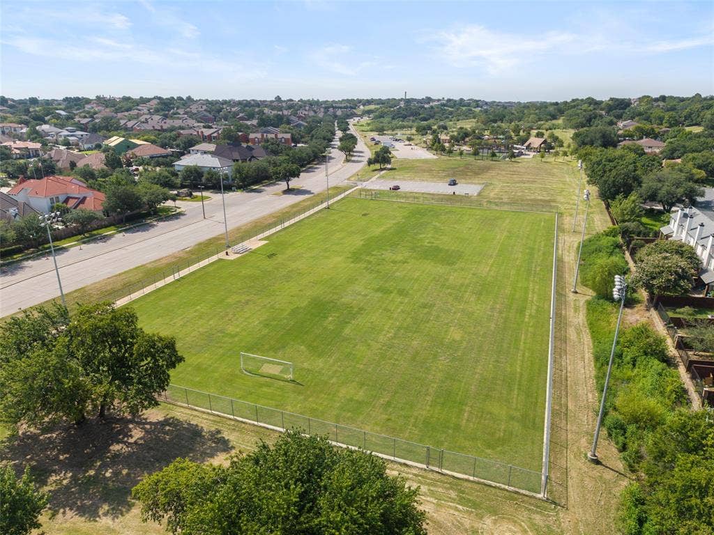 4414 Westminster Drive, Irving, TX 75038 Expansive green field featuring a goalpost, surrounded by a fence and mature trees