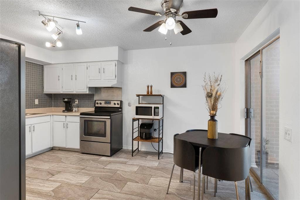 4414 Westminster Drive, Irving, TX 75038 Kitchen featuring wood-finish tile flooring, white cabinetry, a tiled backsplash, stainless steel appliances, and a ceiling fan