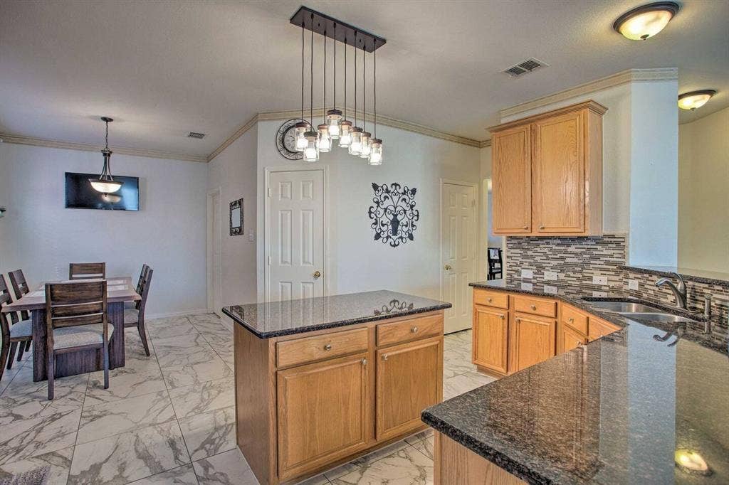 1950 Garrison Way, Garland, TX 75040 Kitchen featuring wood cabinetry, granite countertops, a decorative tile backsplash, and an island with a pendant light fixture