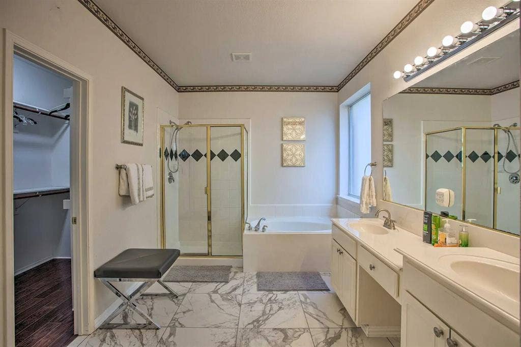 1950 Garrison Way, Garland, TX 75040 Dual vanity with integrated sinks, a built-in soaking tub, a separate glass-enclosed shower, and marble-finish tile flooring
