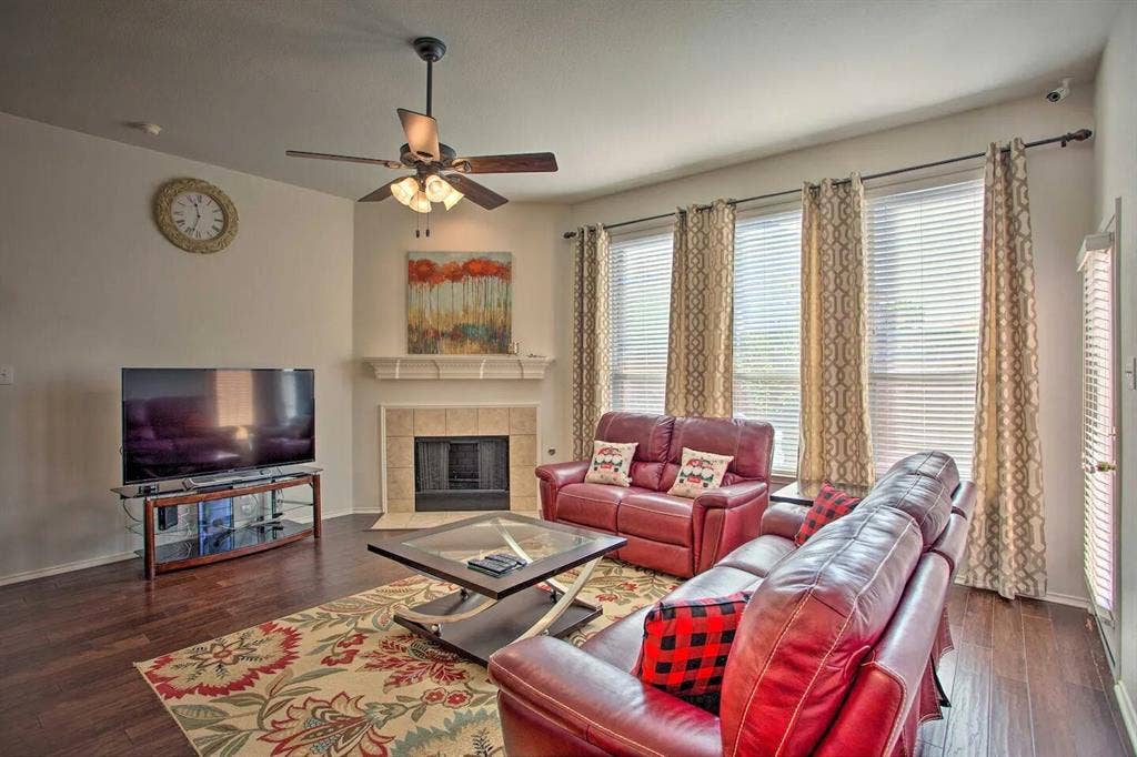 1950 Garrison Way, Garland, TX 75040 Wood-finish flooring throughout, multiple windows with blinds, built-in fireplace with tile surround, ceiling fan with integrated lighting