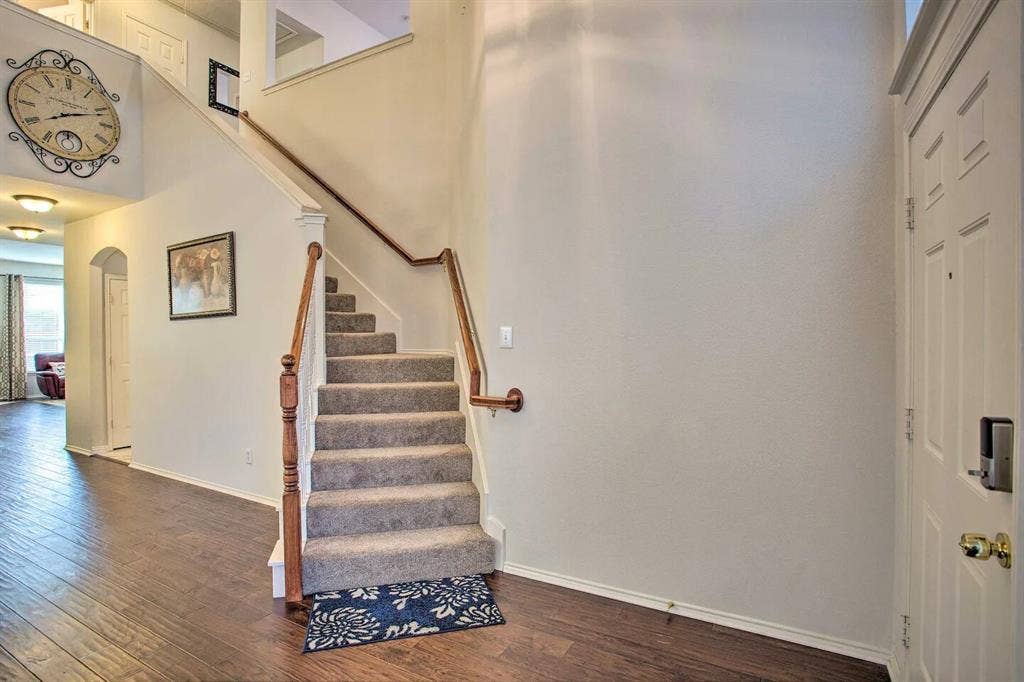 1950 Garrison Way, Garland, TX 75040 Wood-finish flooring, carpeted staircase with wood handrails, overhead recessed lighting, and a paneled entry door
