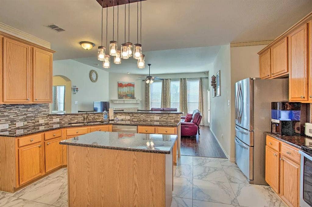 1950 Garrison Way, Garland, TX 75040 Kitchen featuring wood cabinetry, granite countertops, a mosaic tile backsplash, stainless steel appliances, and an island with pendant lighting