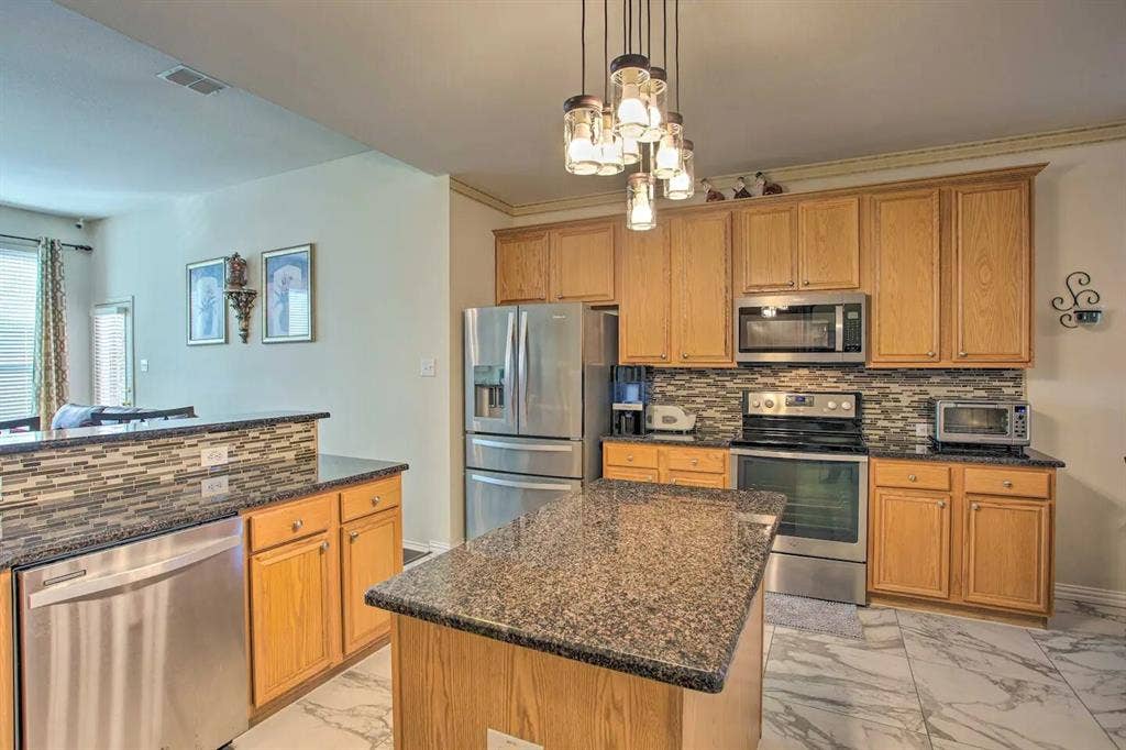 1950 Garrison Way, Garland, TX 75040 Kitchen featuring a central island, wood cabinetry, stone countertops, and stainless steel appliances