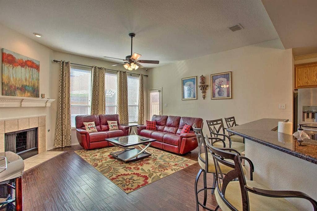 1950 Garrison Way, Garland, TX 75040 Open-concept living space featuring wood-finish flooring, a tiled fireplace with a mantel, and multiple windows