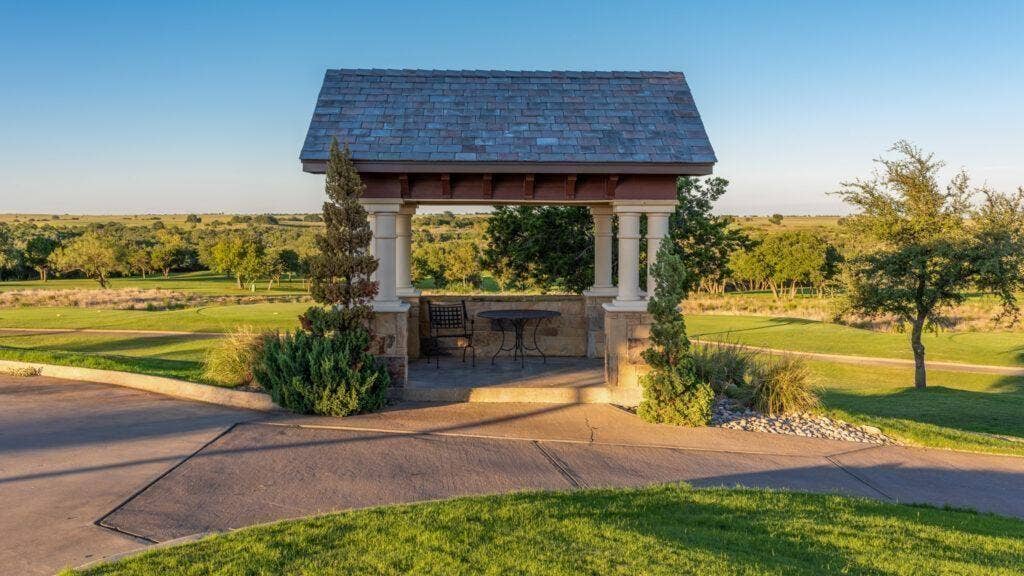 Stone-clad gazebo with column supports and a shingle roof