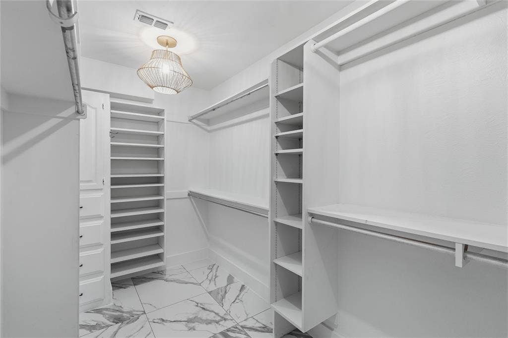 White custom closet system with hanging rods, integrated shelving units, and a built-in drawer cabinet