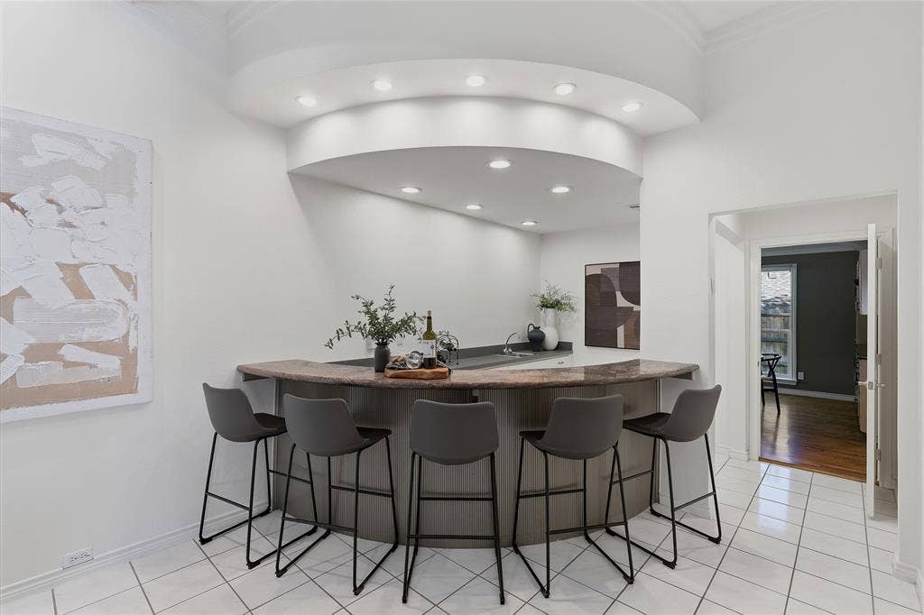 Built-in bar with a stone countertop, recessed lighting, and tile flooring