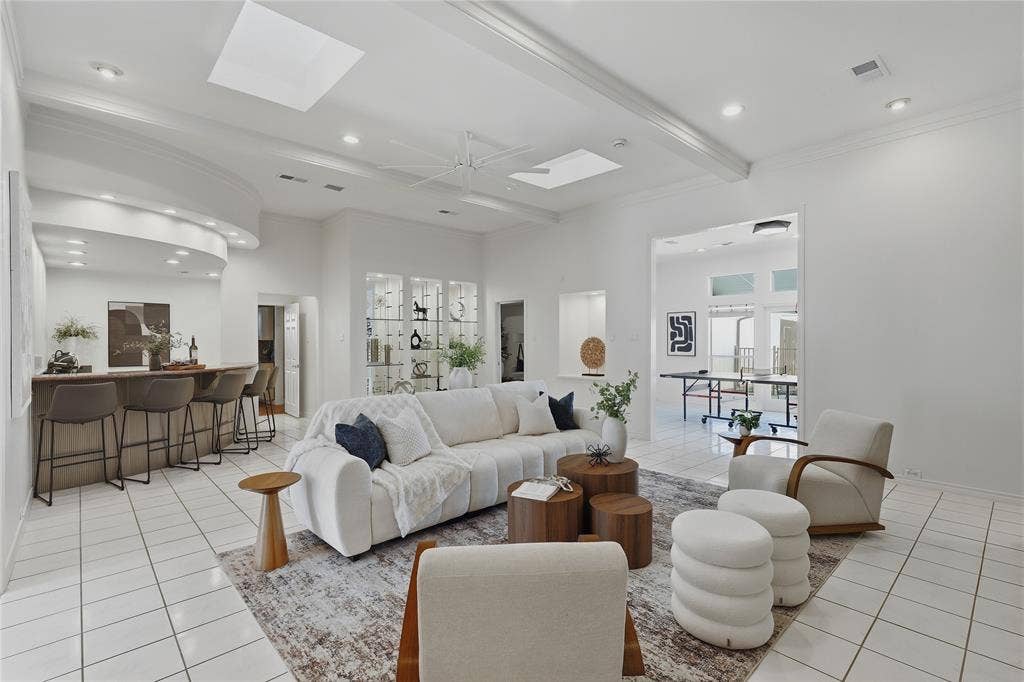 Spacious living area featuring white tile flooring, recessed lighting, and a built-in wet bar with a curved counter