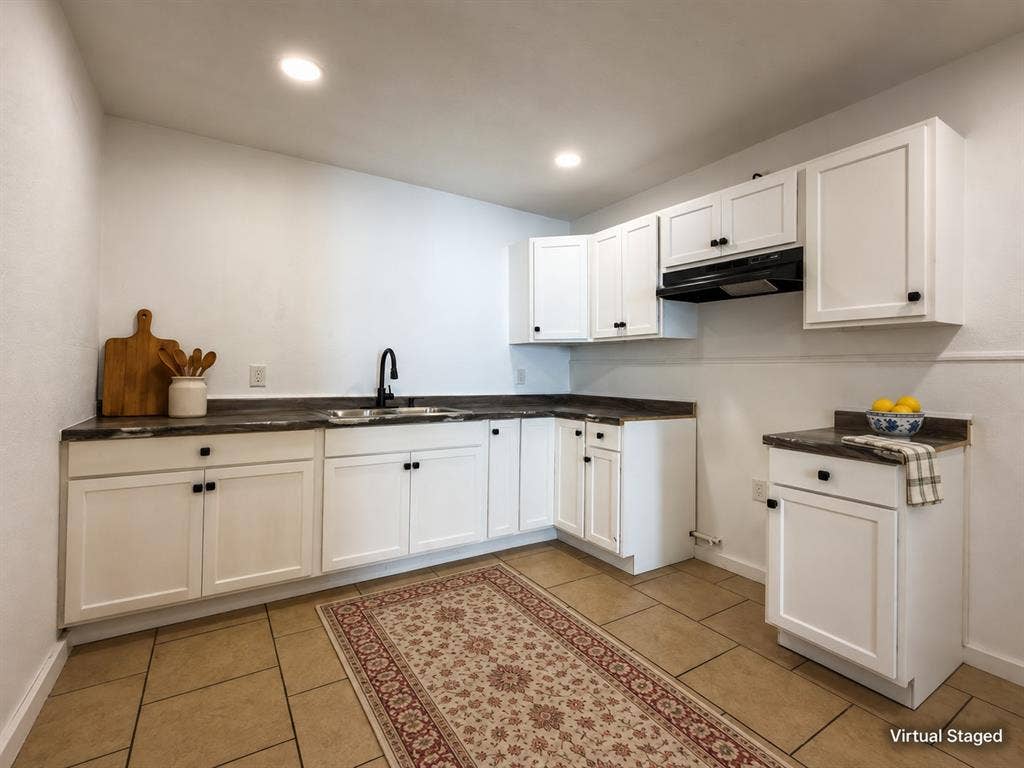 3709 N 22nd Street, Waco, TX 76708 White shaker cabinetry with dark hardware, dark countertops, a black gooseneck faucet, an undermount sink, and tiled flooring