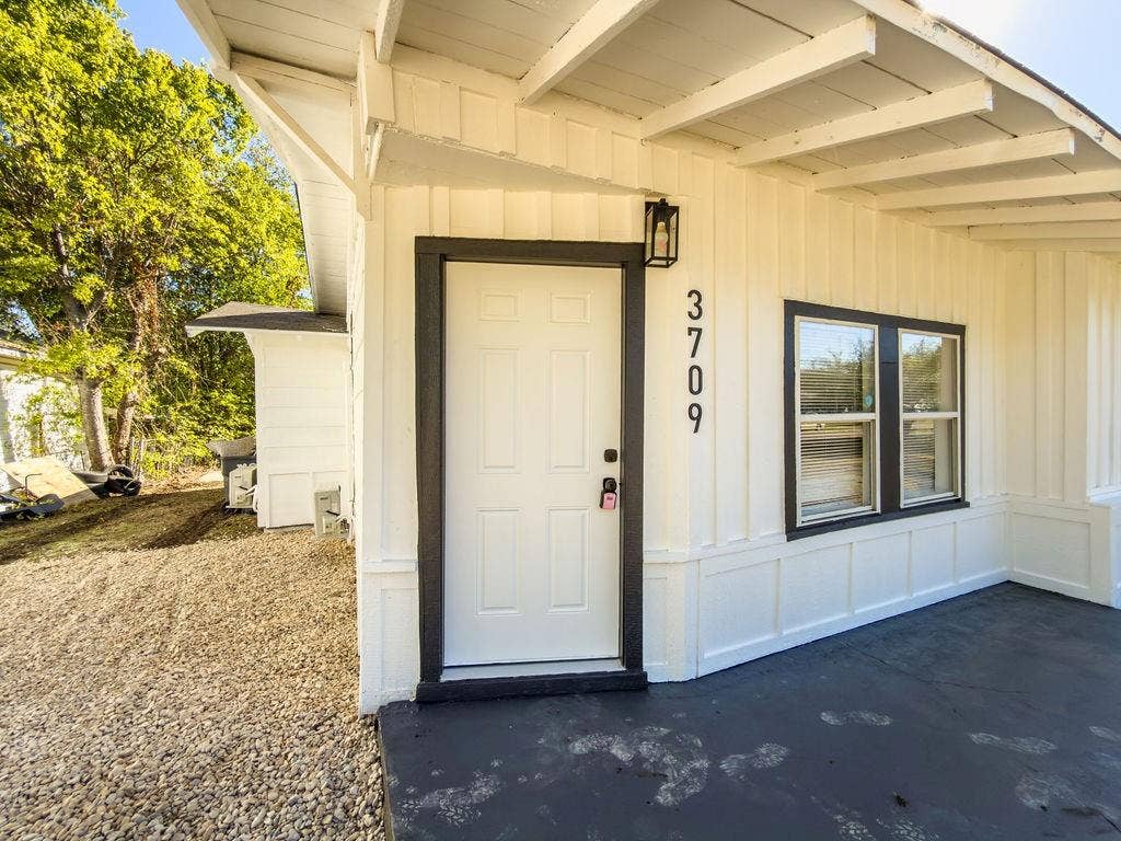 3709 N 22nd Street, Waco, TX 76708 Vertical board and batten siding, black trimmed windows, black entry door, black exterior lighting, and a black painted porch