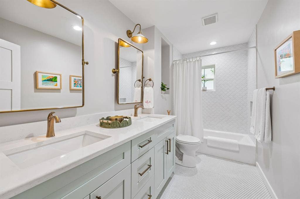 10428 Vinemont, Dallas, TX 75218 Dual sink vanity with light-toned cabinetry and integrated sinks, brushed gold-tone fixtures, and white tile flooring