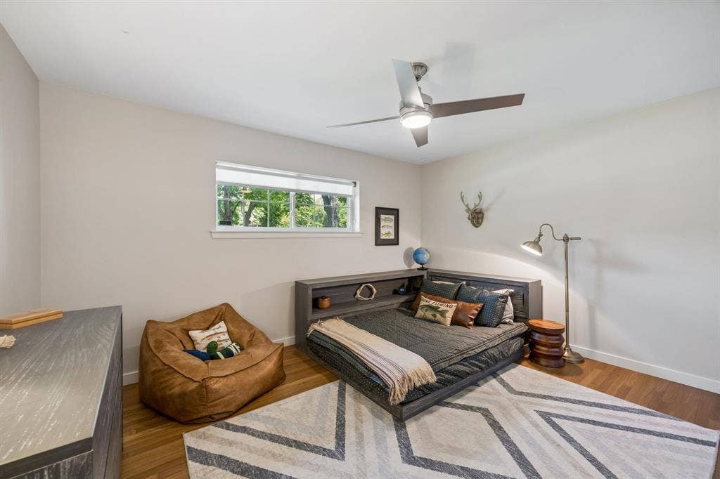 10428 Vinemont, Dallas, TX 75218 Hardwood flooring, neutral wall tones, modern ceiling fan, built-in shelving, and a bright window