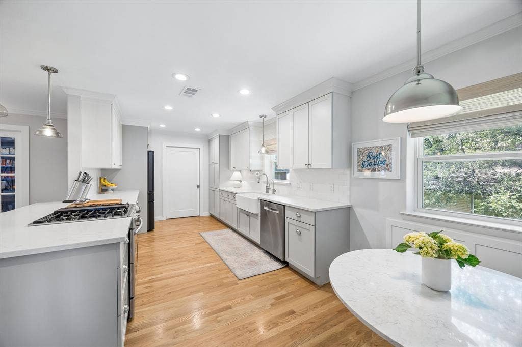 10428 Vinemont, Dallas, TX 75218 Light wood-finish flooring, white shaker cabinetry, white countertops, stainless steel appliances, and recessed lighting