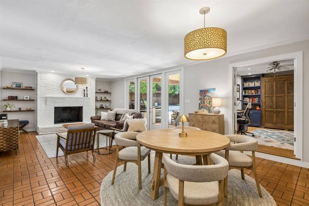 10428 Vinemont, Dallas, TX 75218 Brick flooring, white brick fireplace, built-in shelving, French doors, and a decorative pendant light fixture