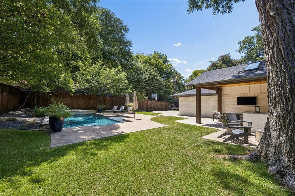 10428 Vinemont, Dallas, TX 75218 Outdoor living area featuring a swimming pool, covered patio, outdoor kitchen, and manicured lawn