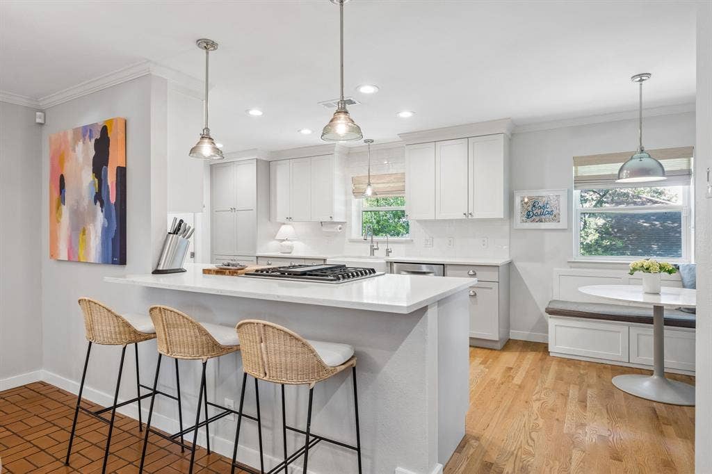 10428 Vinemont, Dallas, TX 75218 White shaker-style cabinetry, light wood-finish flooring, white countertop surfaces, and a built-in banquette seating area