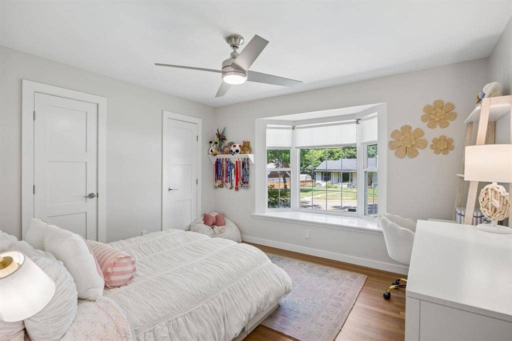 10428 Vinemont, Dallas, TX 75218 Hardwood flooring, bay window with integrated sill, contemporary ceiling fan, and white three-panel interior doors