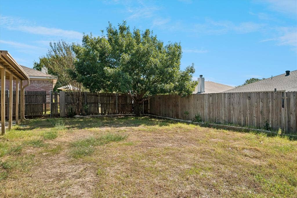 Expansive backyard featuring wood privacy fencing and a mature tree