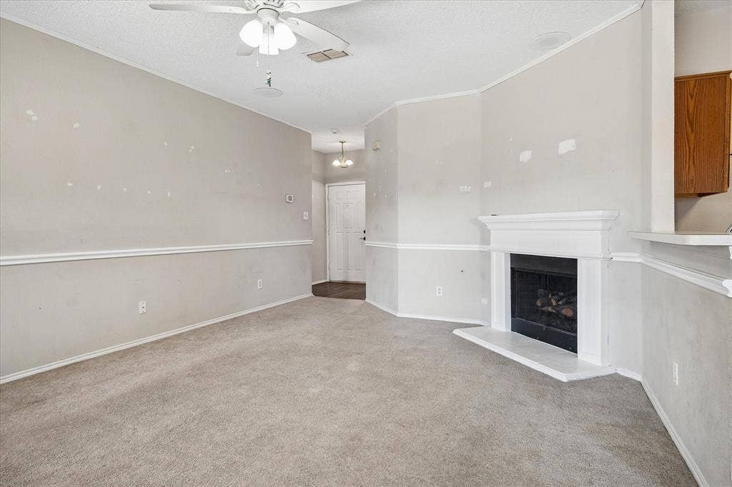 Open-concept living space featuring a ceiling fan, fireplace with a white mantel, and chair rail molding