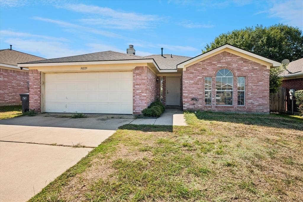 Brick exterior facade with an arched window, single-car garage, and a concrete driveway