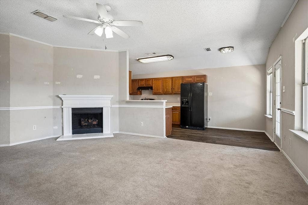 Living area with a fireplace, ceiling fan, and carpeted flooring