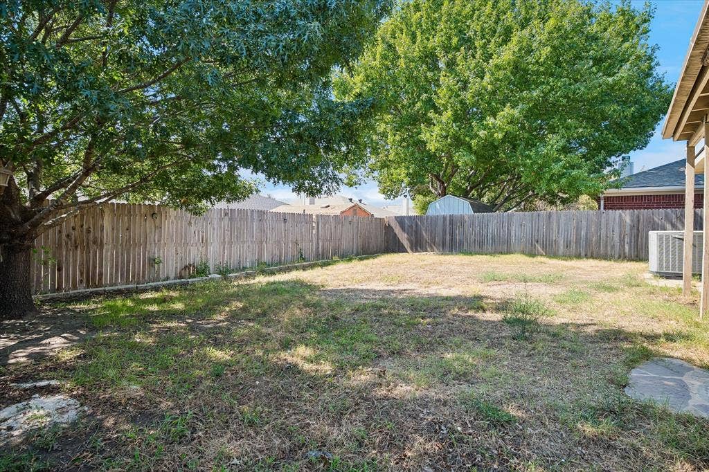 Expansive backyard featuring mature trees and wood fencing