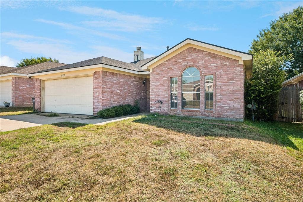 Brick exterior with a prominent arched window, attached garage, and a gabled roofline
