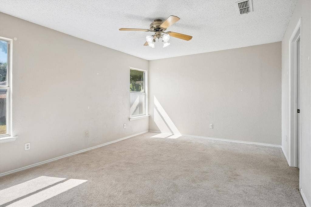 Carpeted flooring, ceiling fan with light fixture, and multiple windows