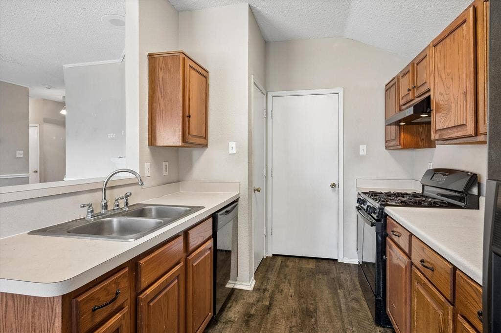 Kitchen featuring wood-finish flooring, a stainless steel double basin sink, and a black gas range