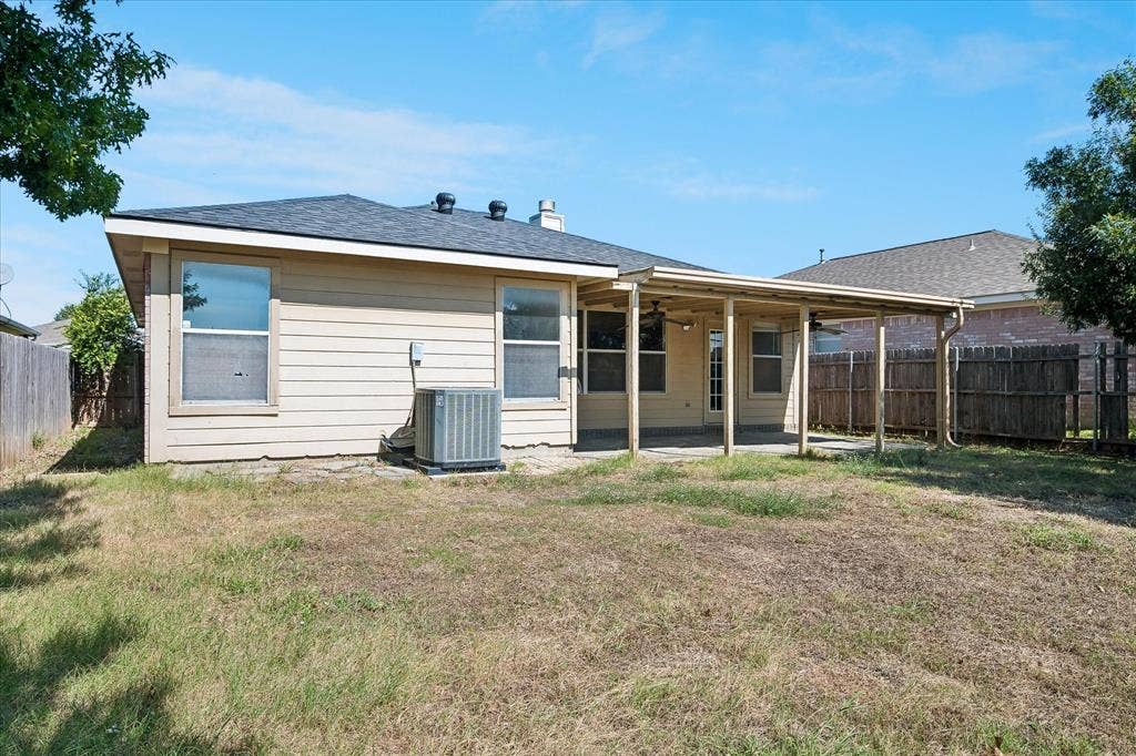Expansive backyard featuring a covered patio, multiple windows, and a privacy fence