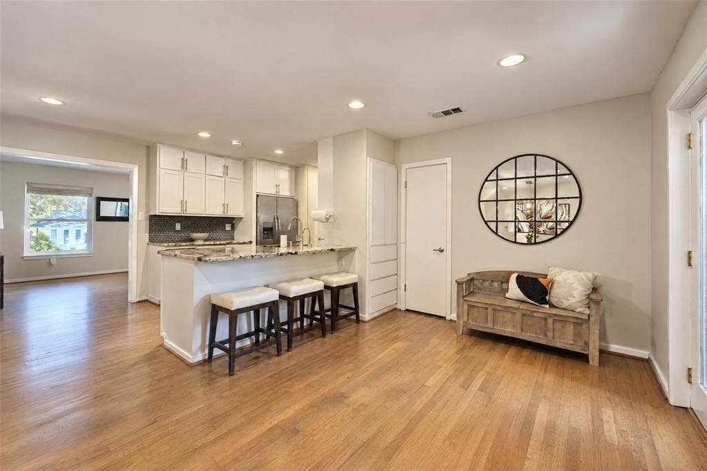 6866 Burwood Lane, Dallas, TX 75214 Hardwood-finish flooring throughout, recessed ceiling lighting, kitchen island with stone countertop, stainless steel appliances, and white cabinetry