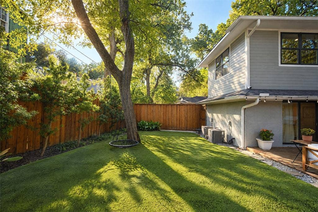 6866 Burwood Lane, Dallas, TX 75214 Expansive lawn area with mature trees, bordered by a wooden privacy fence and established plantings
